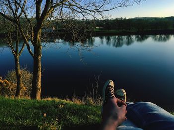 Low section of person on lake by tree