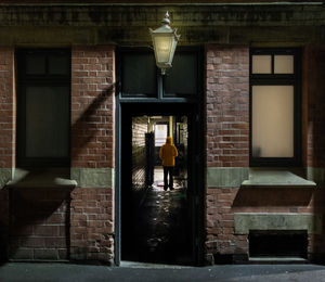 Rear view of woman walking on street amidst building