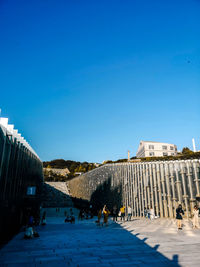 Group of people in front of buildings against blue sky