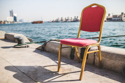 Close-up of deck chairs by sea against clear sky