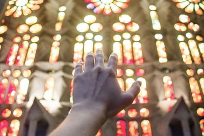 Close-up of hand against stained glass windows in church