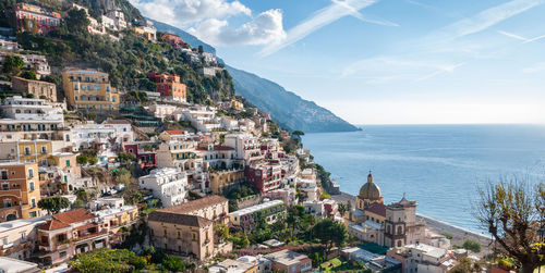 Aerial view of townscape by sea against sky