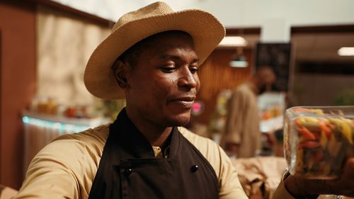 Portrait of young man wearing hat standing in cafe