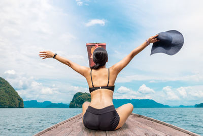 Rear view of man sitting in sea against sky