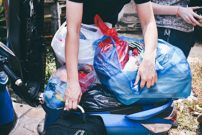 Midsection of women with plastic bags on motorcycle