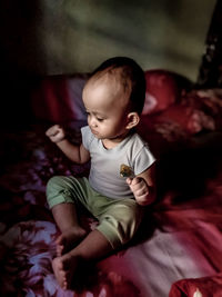 High angle view of baby boy sitting on bed