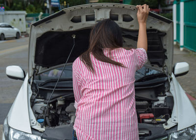 Rear view of woman standing in car