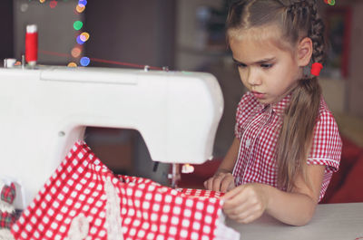 Cute girl using sewing machine