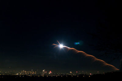 Firework display in city against sky at night