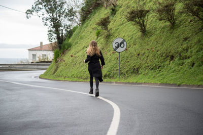 Rear view full length of woman walking on road