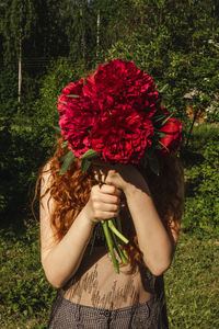 Midsection of woman holding red flower