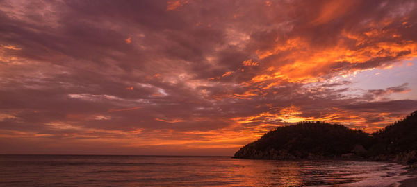 Scenic view of sea against dramatic sky during sunset