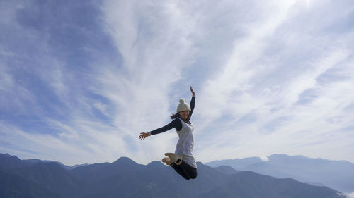 Low angle view of man jumping against sky