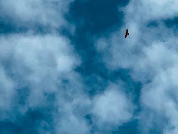 Low angle view of person paragliding against blue sky