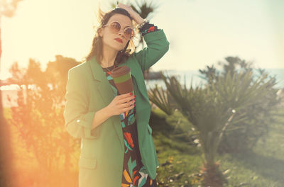 Woman wearing sunglasses while holding coffee cup outdoors