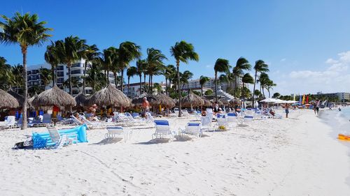 Lounge chairs at beach against sky during sunny day in city