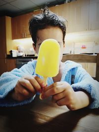 Boy holding flavored ice in kitchen at home
