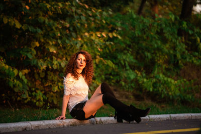 Portrait of young woman sitting against trees