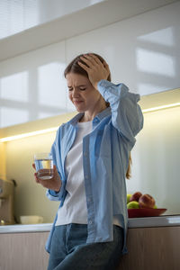 Portrait of young woman using mobile phone while standing at home