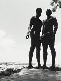 Couple standing at beach against sky