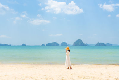 Woman standing on beach against sky