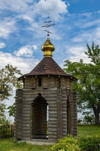 A christian temple made of a wooden frame with a golden dome and a cross.