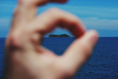 Close-up of island seen through ok sign