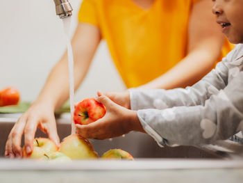 Mother and daughter at home washing apples