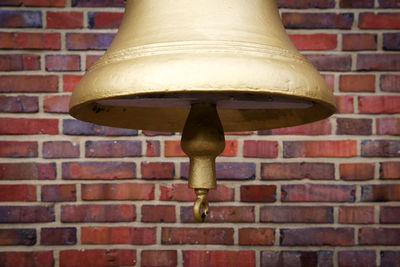 Low angle view of electric lamp against brick wall