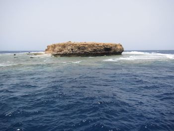 Scenic view of rocks in sea against clear sky