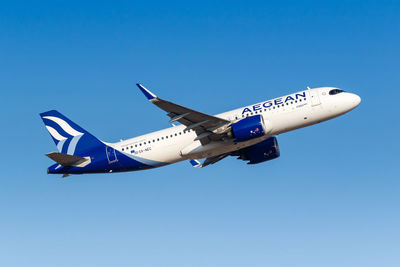 Low angle view of airplane flying against clear blue sky