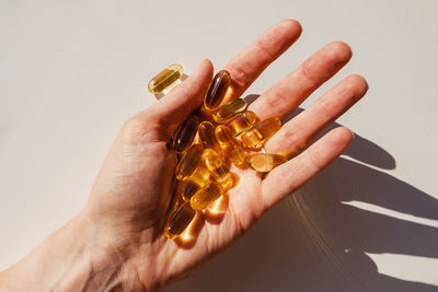 Woman's hand close-up holding a lot of gel pills, vitamin d or omega 3 oil. dietary supplement. 