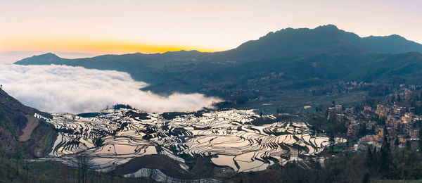 Scenic view of landscape and mountains against sky during sunset