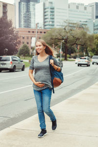 Full length of young woman standing on road in city