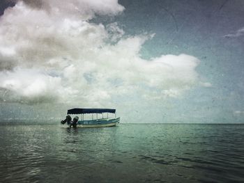 Boat sailing in sea against cloudy sky