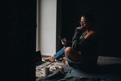 Woman using mobile phone while siting at home