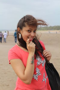 Portrait of girl standing at beach against sky