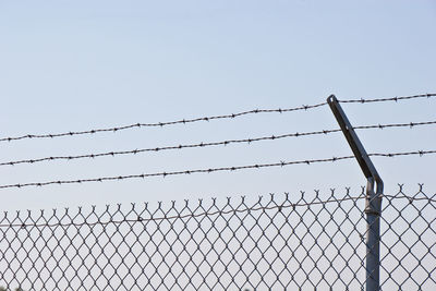 Low angle view of barbed wire fence against sky