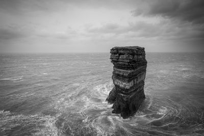 Stack rock in sea against sky