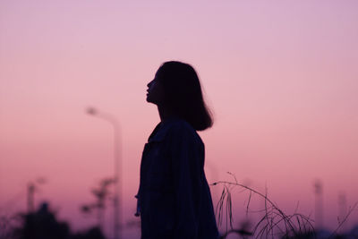 Side view of silhouette woman standing against sky during sunset