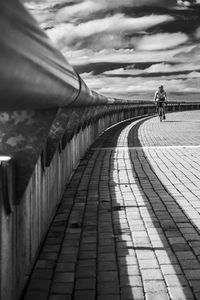 Rear view of woman riding bicycle on footbridge