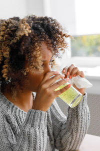 Young woman drinking water while sitting on table