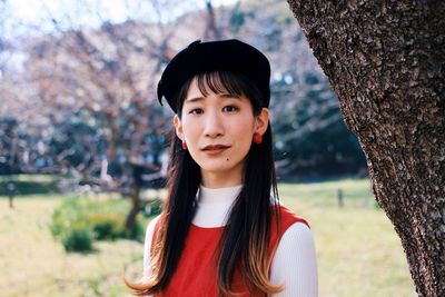 Portrait of teenage girl standing against tree trunk