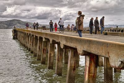 Pier in sea against cloudy sky