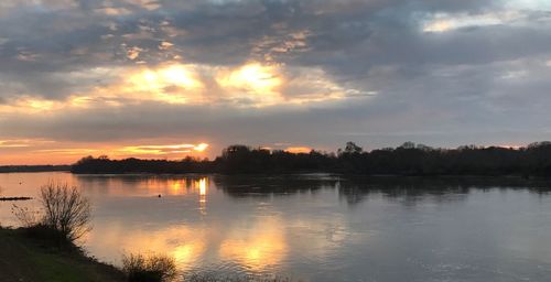 Scenic view of river against sky at sunset