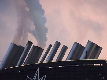 Low angle view of smoke emitting from factory against sky