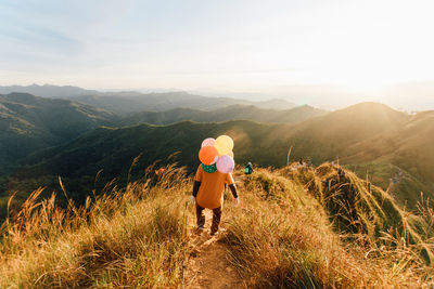 Rear view of man on mountain against sky