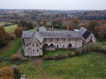 Old house on field by houses against sky