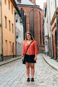 Joyful young woman standing in the street of an old european tow