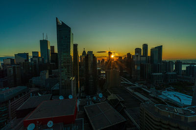 Modern buildings in city against sky during sunset